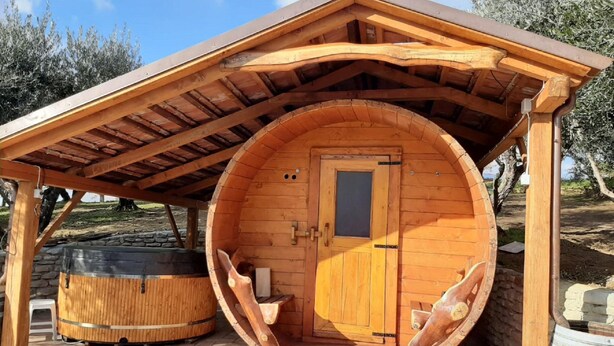A wooden barrel-shaped structure with a door, a hot tub, and a covered patio area. - Peaceful Apartment in Modigliana With Swimming Pool (Modigliana)