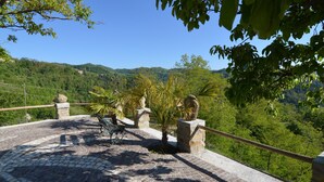 A cobblestone pathway with stone railings and palm trees, leading to a scenic overlook with a view of green hills and a clear blue sky. - Peaceful Apartment in Modigliana With Swimming Pool (Modigliana)