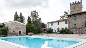 Una piscina con un edificio de piedra y una torre al fondo.