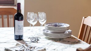Una mesa dispuesta con una botella de vino, copas, platos y cubiertos.