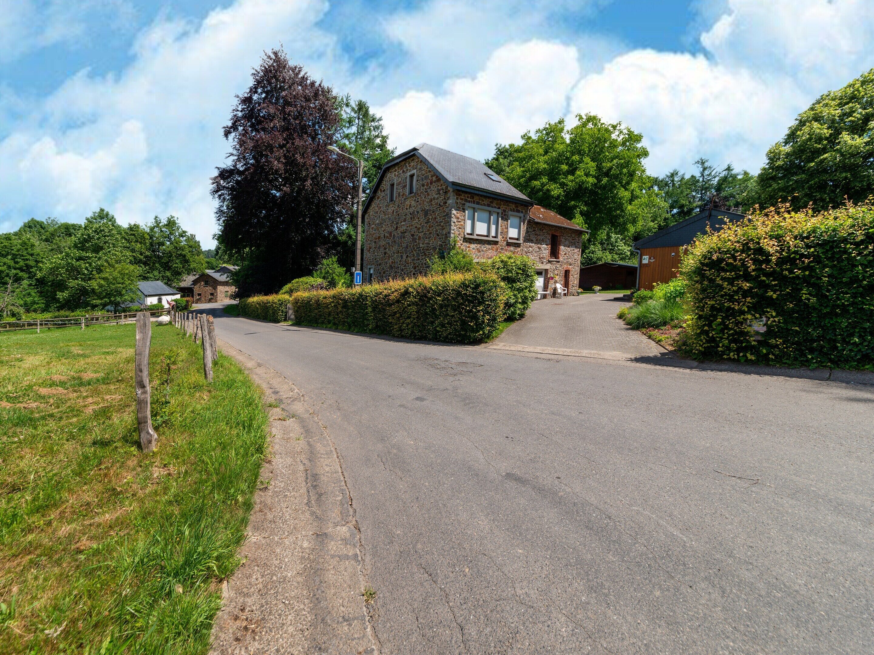 A stone house with a paved driveway leading to a garage.