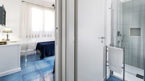 A modern bathroom with a glass shower enclosure, a white sink, and a chair. - Belvilla by OYO Spuma di Mare - Riccio (San Vito Lo Capo)