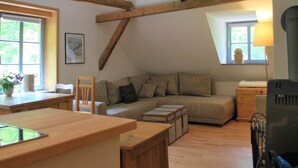A cozy living room with a wooden ceiling, a sofa, a table, and a lamp. - Watermill Stay With Garden (Heringen)