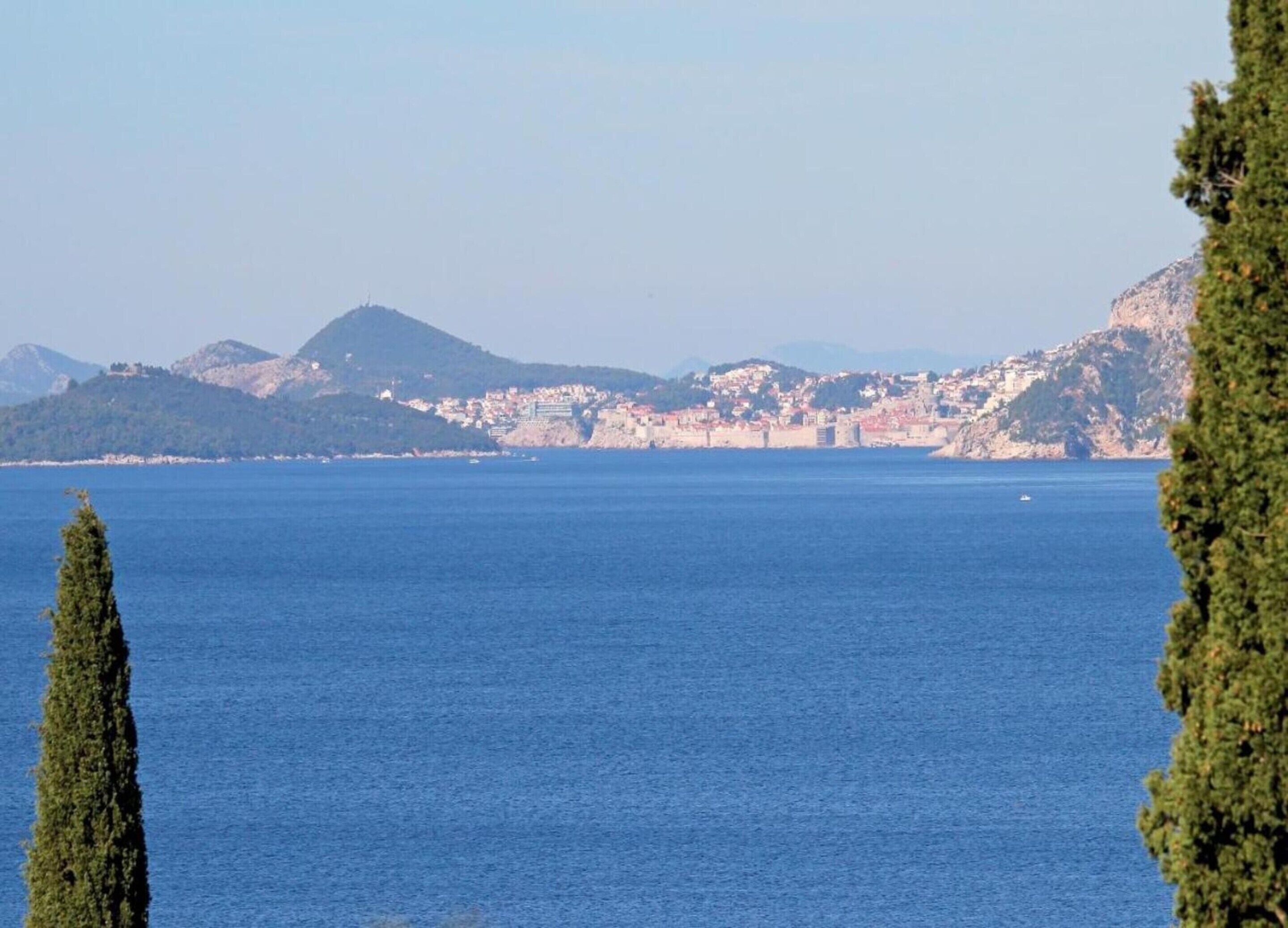 Eine Küstenstadt mit freiem Blick auf das Meer und Berge im Hintergrund.