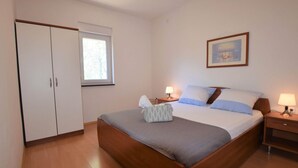 Une chambre à coucher avec un lit en bois, deux tables de chevet avec des lampes, une fenêtre et une armoire.