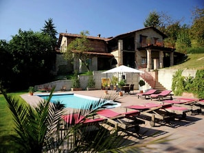 A villa with a swimming pool, outdoor seating, and a staircase leading to the upper floor.