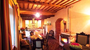 A cozy dining area with a fireplace, wooden furniture, and a brick floor. - Mansion in Langhe With Pool and Winery Charm (Bastia Mondovì)