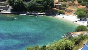 Una zona costiera con acque cristalline turchesi, imbarcazioni e una spiaggia con ombrelloni.