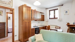 Une cuisine compacte avec des meubles en bois, un coin repas avec une table et des chaises, et un canapé vert.