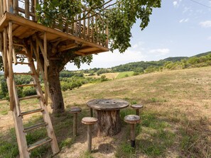 A wooden treehouse with a ladder, a round wooden table, and four stools. - Apartment in Umbria Near Majestic Mountains (Assisi)