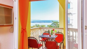 A balcony with a table and chairs, a view of the sea, and a door with a curtain. - Serene Apartment in Dramalj with Hot Tub (Crikvenica)