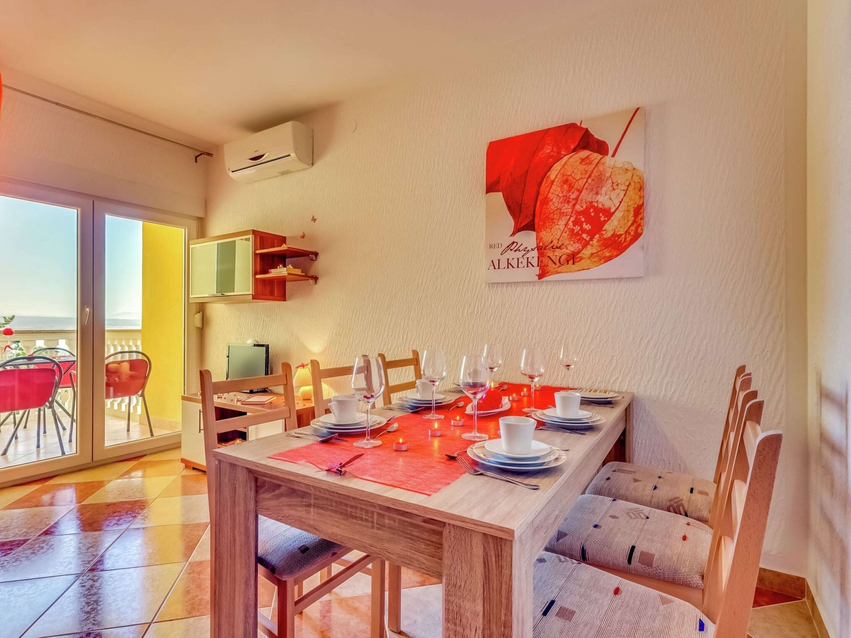 A dining area with a wooden table set for four, a red placemat, and a wall-mounted air conditioner.