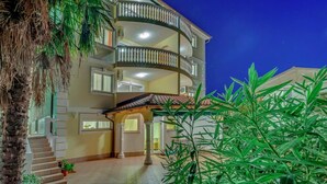 A multi-story building with a balcony, a covered entrance, and a tiled patio area. - Luxurious Apartment in Kvarner by Sea (Crikvenica)