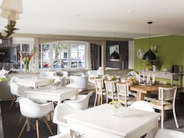 Un comedor moderno con mobiliario blanco, una mesa de comedor de madera y una pared de acento verde.