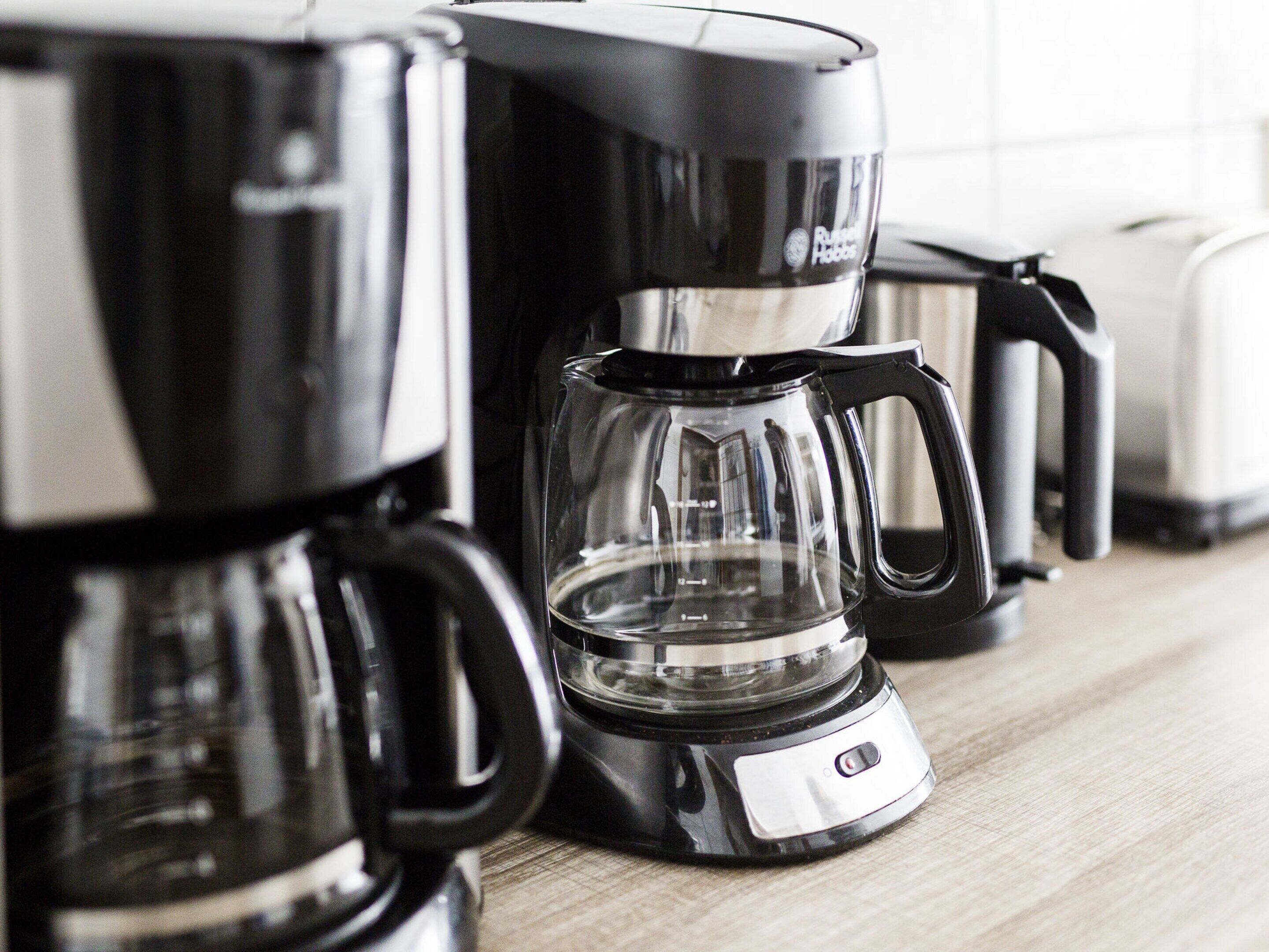 A coffee maker with a transparent water reservoir and a black base, placed on a wooden surface.