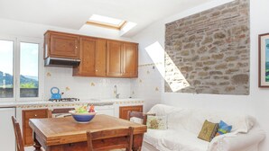 A kitchen with wooden cabinets, a dining table, and a white sofa. - Heart of Emilia-romagna Apartment (Modigliana)
