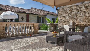 A courtyard with stone walls, a tiled roof, wicker furniture, and a fruit bowl. - Heart of Emilia-romagna Apartment (Modigliana)