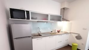 A compact kitchen with a refrigerator, microwave, and sink. - Apartment by the Beach in Dalmatia (Bilice)