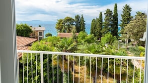 Un balcon donnant sur la mer, entouré de verdure et de bâtiments.