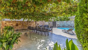 Eine Terrasse im Freien mit Steinmauer, Pool und Tisch mit Stühlen.