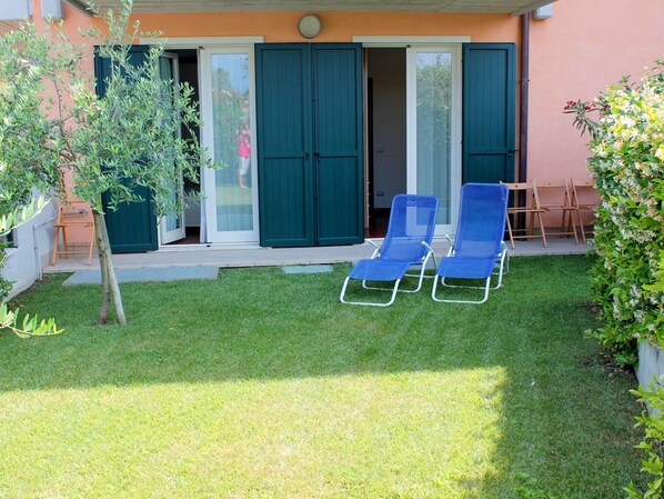 A patio with two blue lounge chairs, a small table, and a sliding glass door leading to a covered area. - Elegant Holiday Home in Lazise with Swimming Pool near Lake (Lazise)