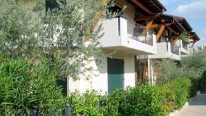 A multi-story building with balconies, surrounded by lush greenery. - Elegant Holiday Home in Lazise with Swimming Pool near Lake (Lazise)
