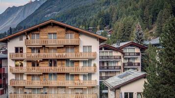 Un hôtel à plusieurs étages, doté de balcons en bois, qui se dresse sur un paysage montagneux.