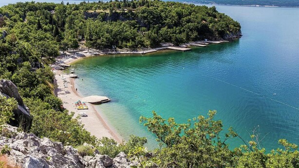 A coastal area with a beach, clear turquoise waters, and a forested peninsula. - Villa in Croatia Near Beach With Pool (Crikvenica)