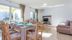 A modern living room with a dining area, a sofa, and a TV. - Villa in Croatia Near Beach With Pool (Crikvenica)