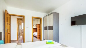 A hotel room with a bed, a TV, a wardrobe, and a bathroom visible through an open door. - Villa in Croatia Near Beach With Pool (Crikvenica)