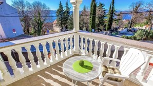 A sunlit outdoor seating area with a round table and white chairs, surrounded by a white balustrade. - Villa in Croatia Near Beach With Pool (Crikvenica)