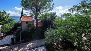 Une maison avec un toit recouvert de tuiles rouges, entourée de verdure et offrant une vue dégagée sur la mer.