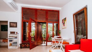 Un salon chaleureux avec un canapé rouge, une table basse en bois et un meuble TV blanc.