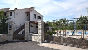 Un immeuble résidentiel sécurisé, doté d’une entrée en pierre, d’un escalier apparent et d’un espace piscine avec des chaises longues.
