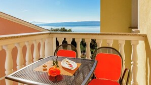A balcony with a table set for two, featuring a rose and a plate of appetizers. - Alluring Apartment in Dramalj with Hot Tub (Crikvenica)