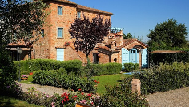 A brick building with a garden, a blue door, and a satellite dish.