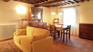 A cozy living room with a sofa, dining table, chairs, and a wooden cabinet.