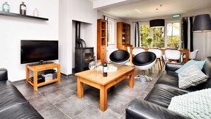 A modern living room with a flat-screen TV, a wooden coffee table, black leather sofas, and a fireplace. - Cozy Stay Near Durbuy Woods (Durbuy)