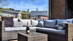 An outdoor seating area with wicker furniture, a bottle of champagne, and glasses. - Cozy Stay Near Durbuy Woods (Durbuy)
