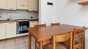 A compact kitchen with a dining table and chairs, a stove, oven, and a small window. - Vibrant Holiday Home in Lazise with Swimming Pool near 2 Lakes (Lazise)