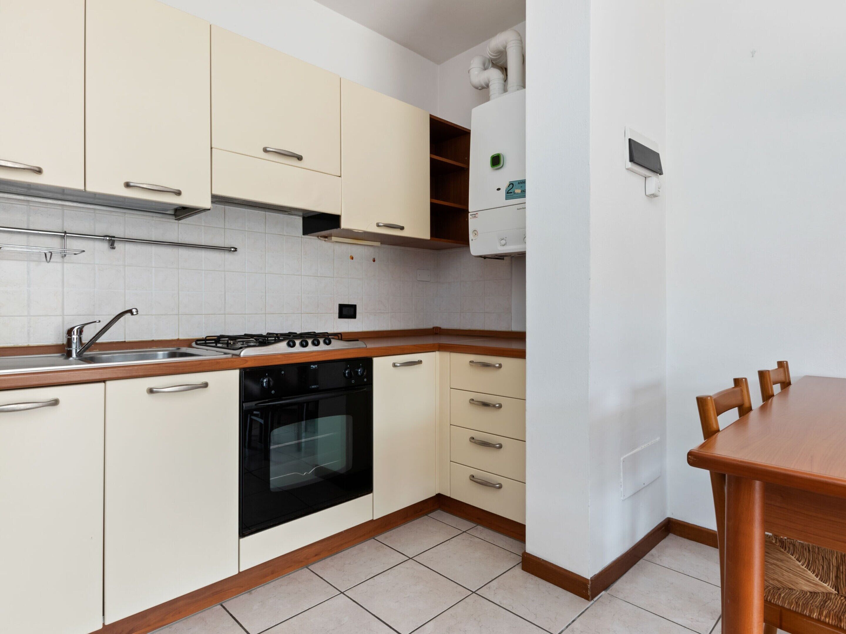 A compact kitchen with white cabinets, a black stove, and a wooden countertop.