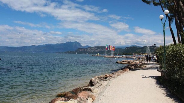A coastal walkway with a clear view of the sea, rocky shoreline, and distant mountains. - Vibrant Holiday Home in Lazise with Swimming Pool near 2 Lakes (Lazise)