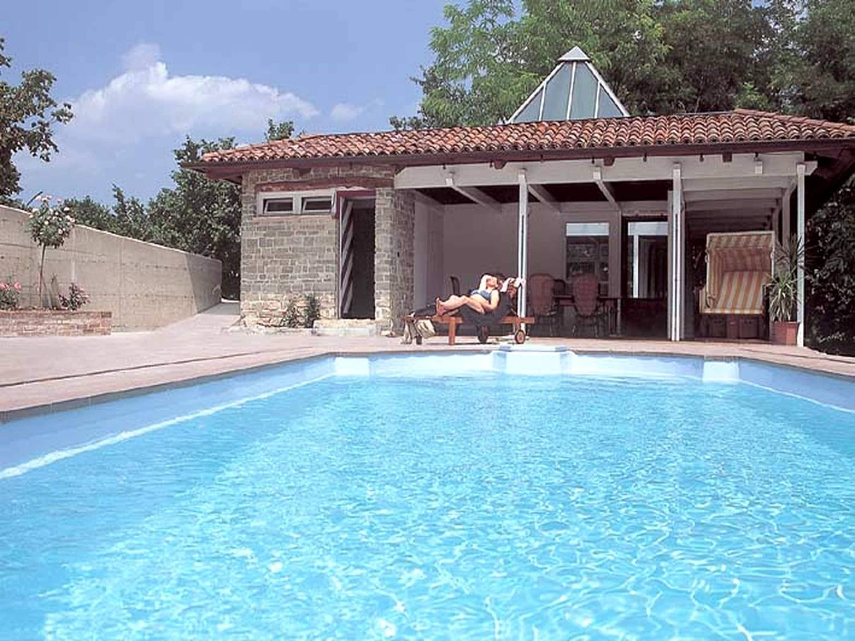 Una piscina con un edificio de piedra al fondo.