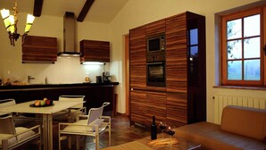 Een moderne keuken met houten lambrisering, een eethoek met stoelen, een bank en een tafel met wijnglazen en een fles.