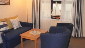 Ett mysigt vardagsrum med en soffa, två fåtöljer, ett soffbord och ett fönster med gardiner.
