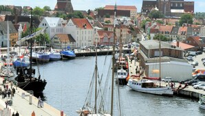 En hamn med förtöjda båtar, ett markant klocktorn och historiska byggnader.