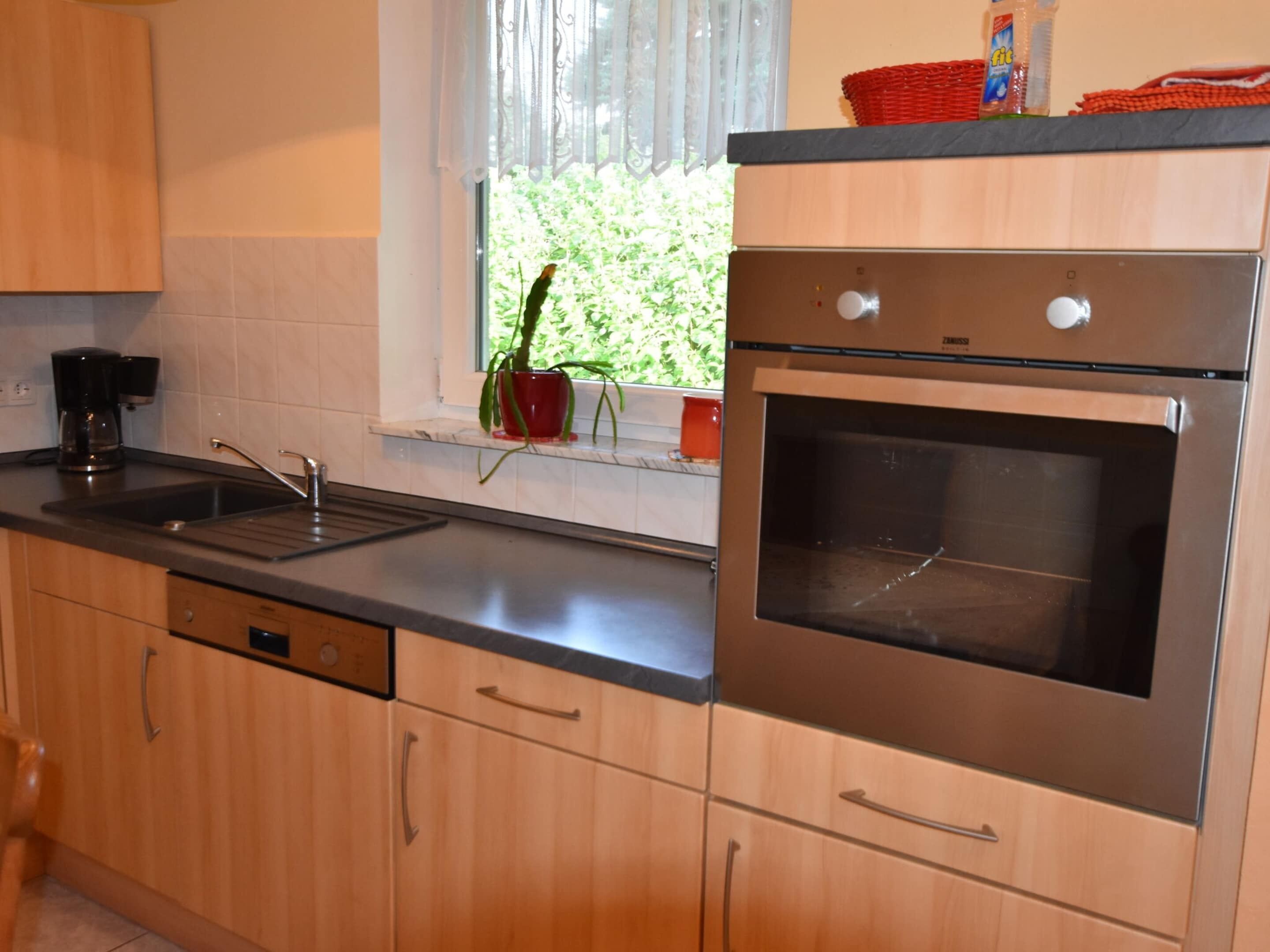 A kitchen with stainless steel appliances, a sink, and wooden cabinets.