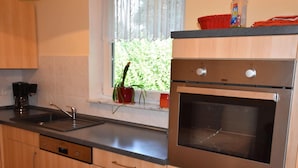 A kitchen with stainless steel appliances, a sink, and wooden cabinets.
