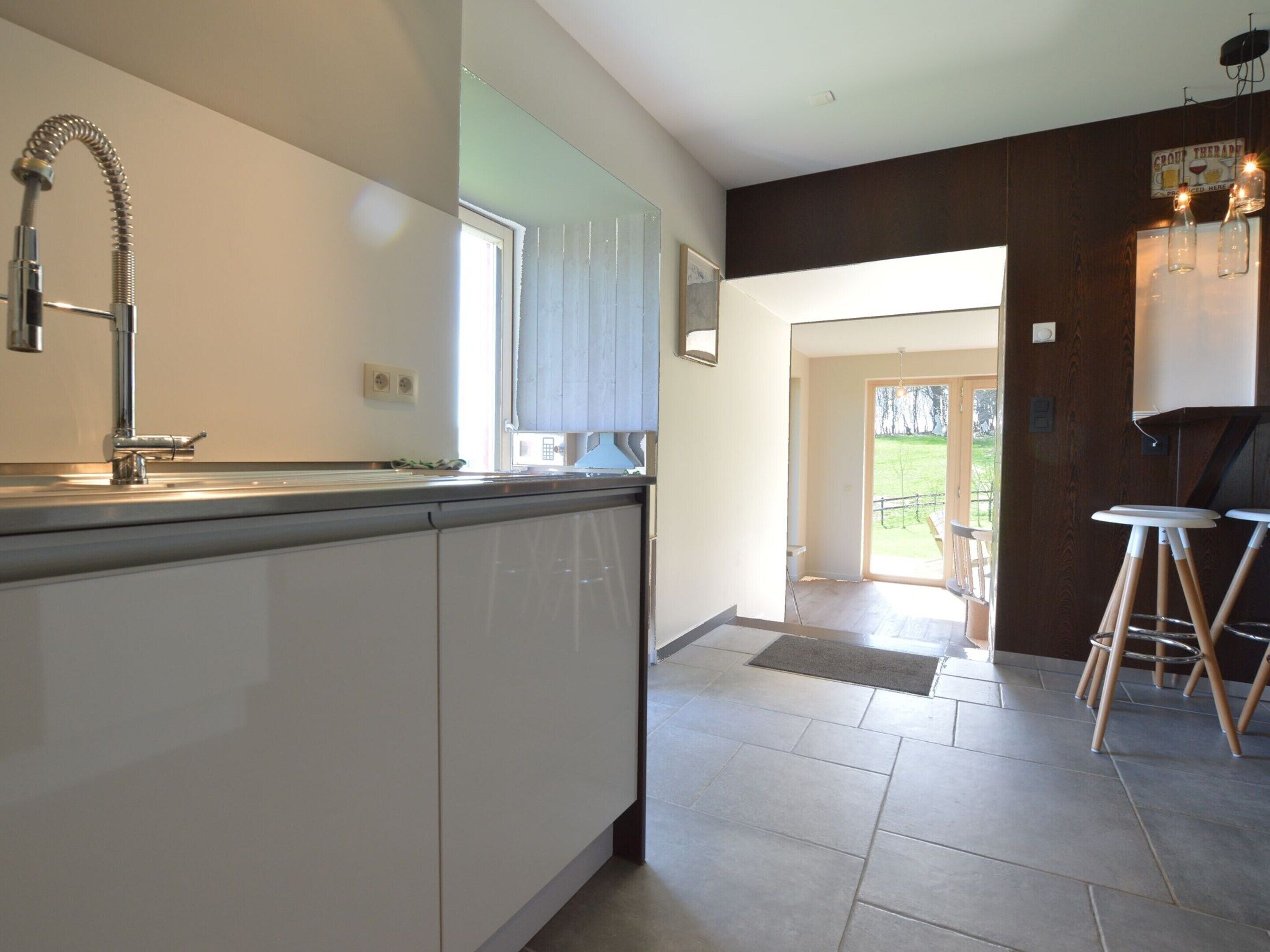 Una cocina moderna con una isla grande, horno empotrado y una ventana. Hay una puerta que da a un patio.