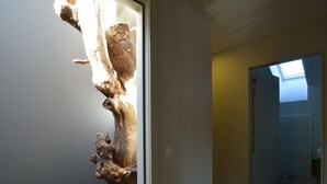 A hallway with a wooden sculpture, a door leading to another room, and a skylight.